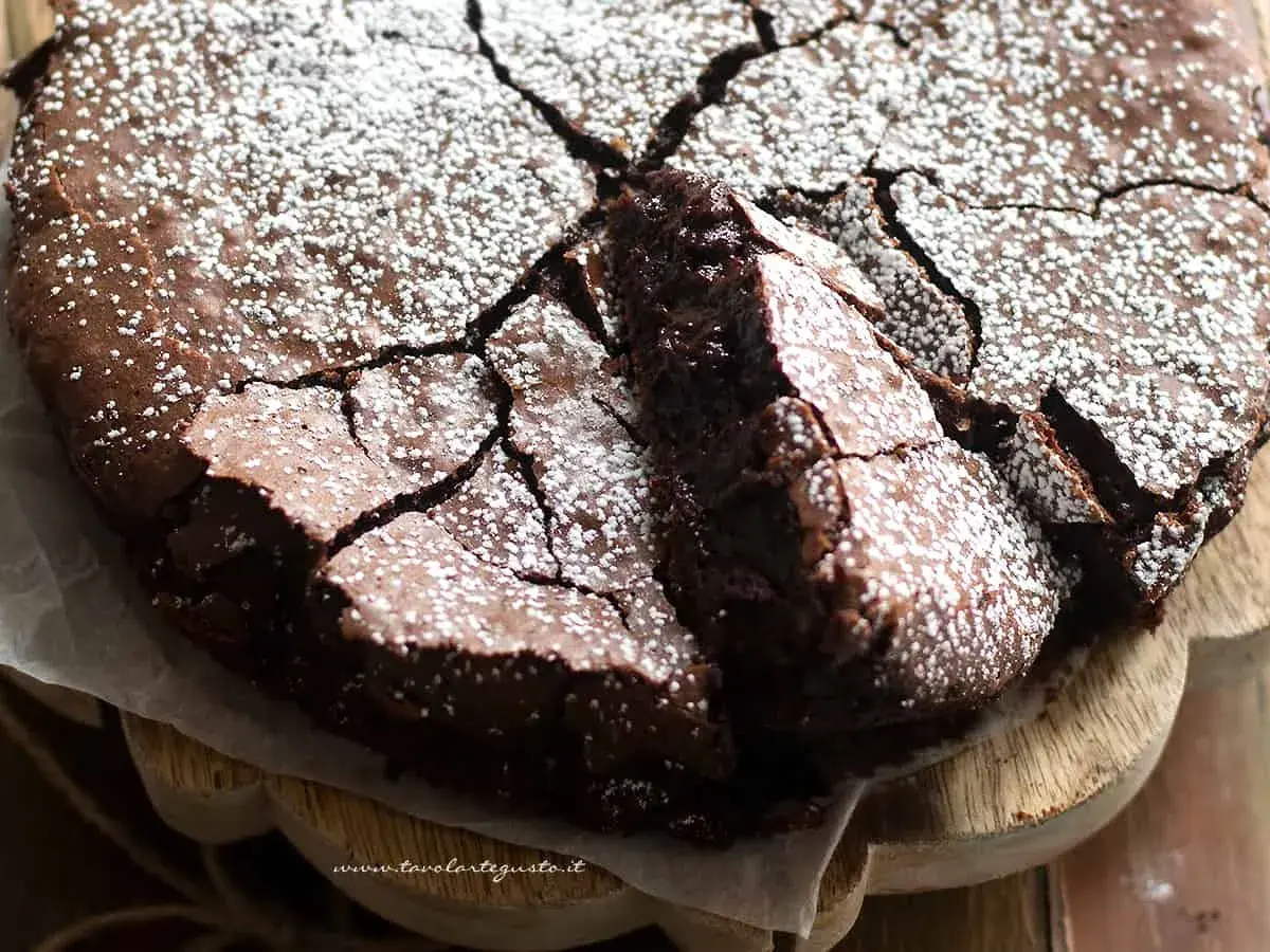 Torta al cioccolato fondente, con una crosta screpolata e cosparsa di zucchero a velo, pronta per essere gustata.