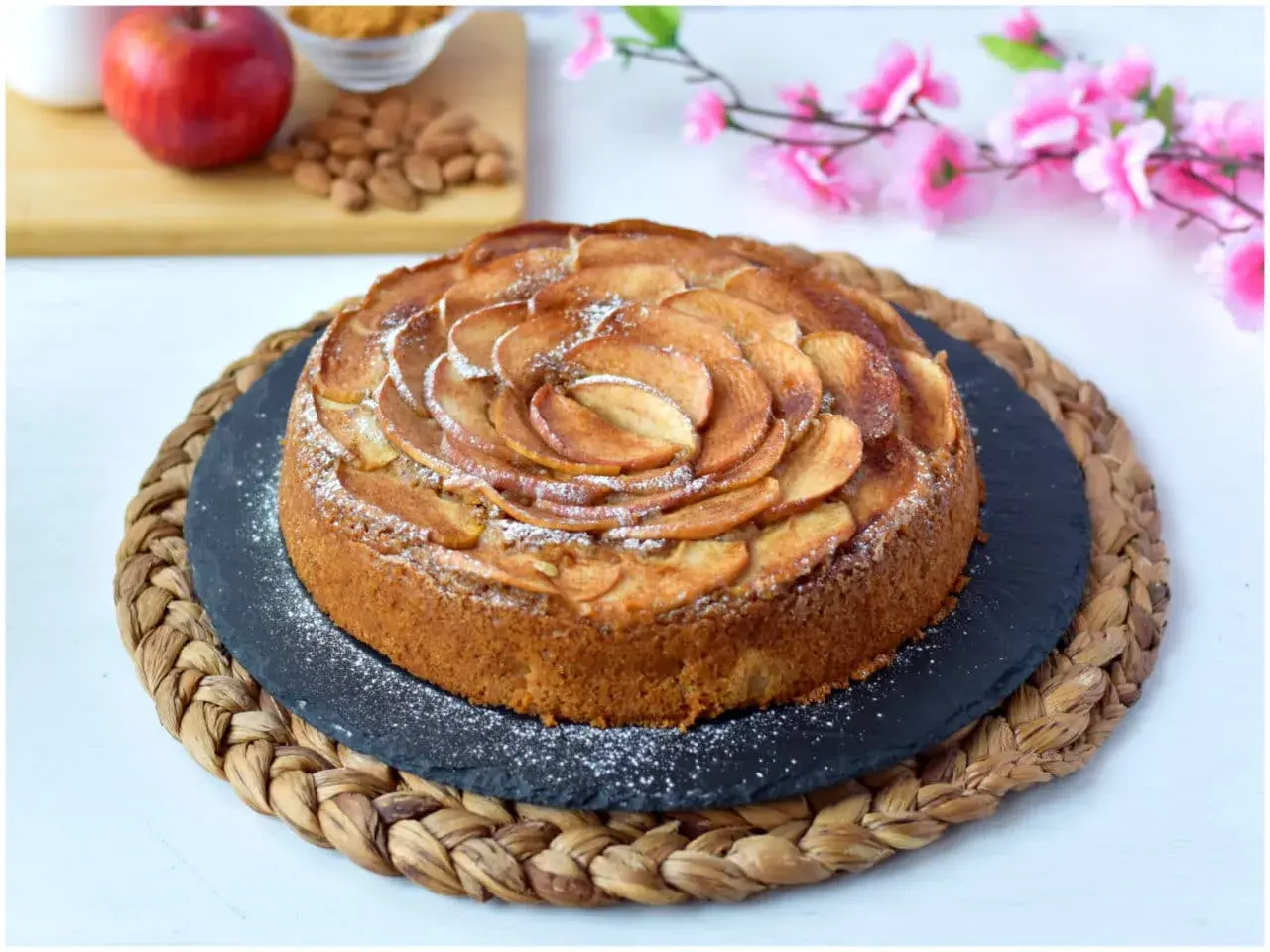 Deliziosa torta di mele vegana, decorata con fettine di mela disposte a spirale e spolverata di zucchero a velo.