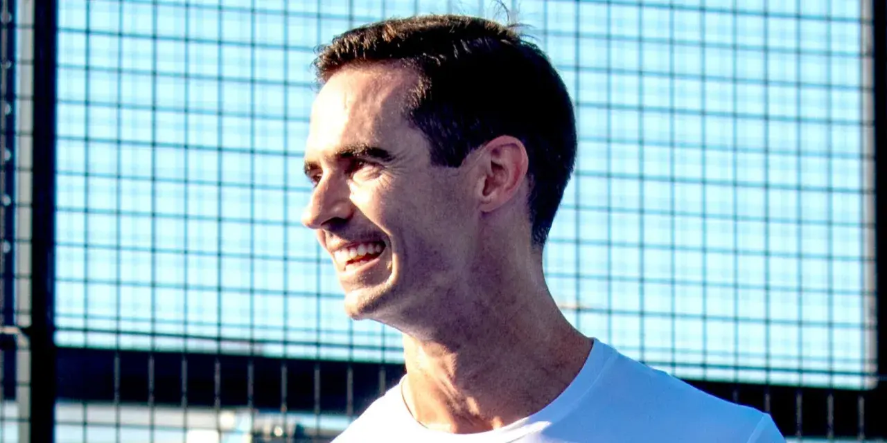 Un uomo sorride con entusiasmo, pronto per una partita di padel.
