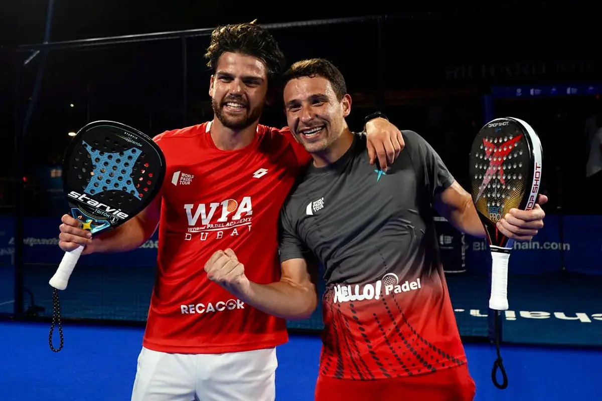Lucas Campagnolo e il suo compagno festeggiano una vittoria nel padel, sorridenti con le racchette in mano.