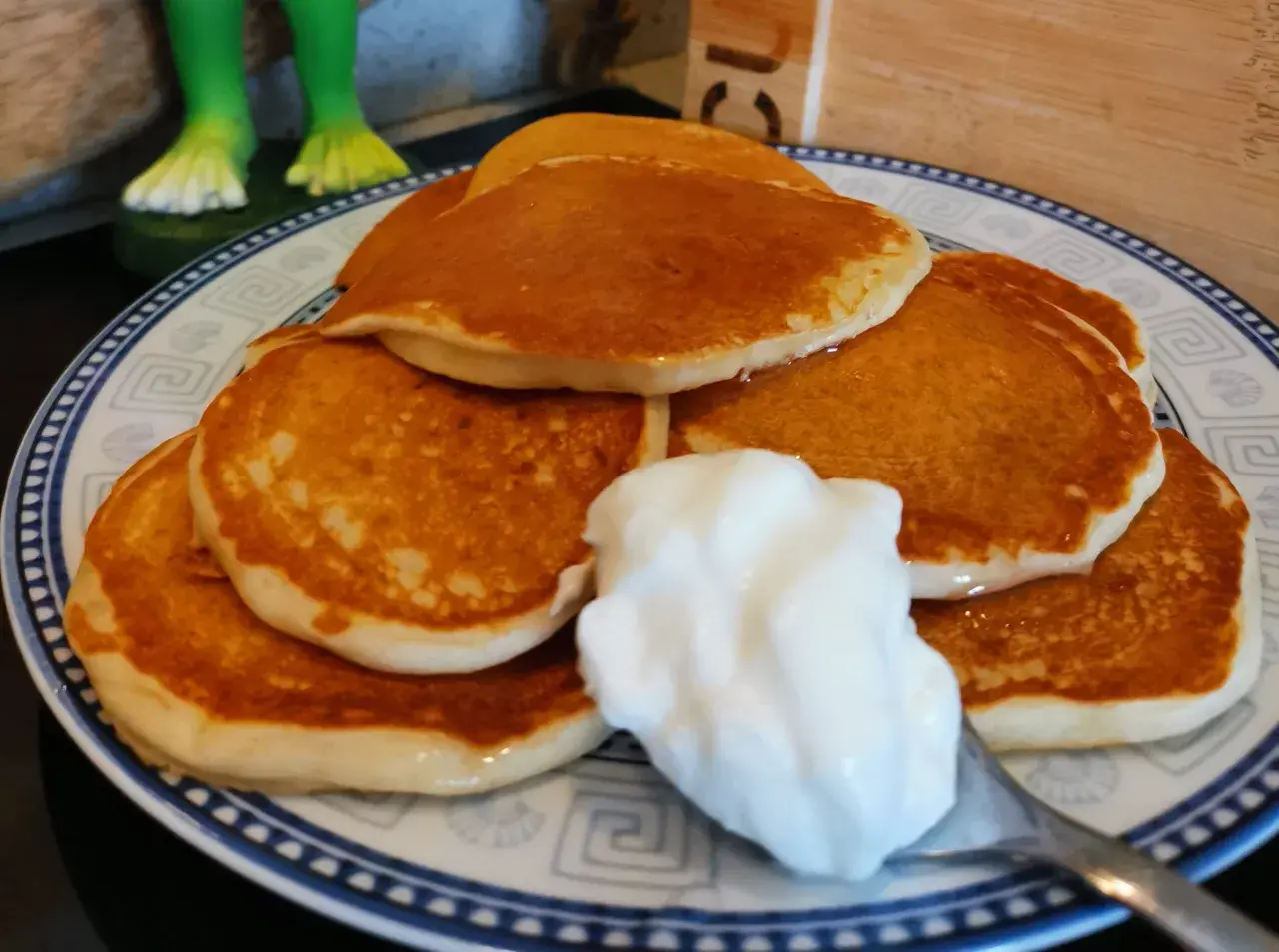 Pancake senza uova con yogurt, una pila dorata su un piatto decorato, pronta per essere gustata.