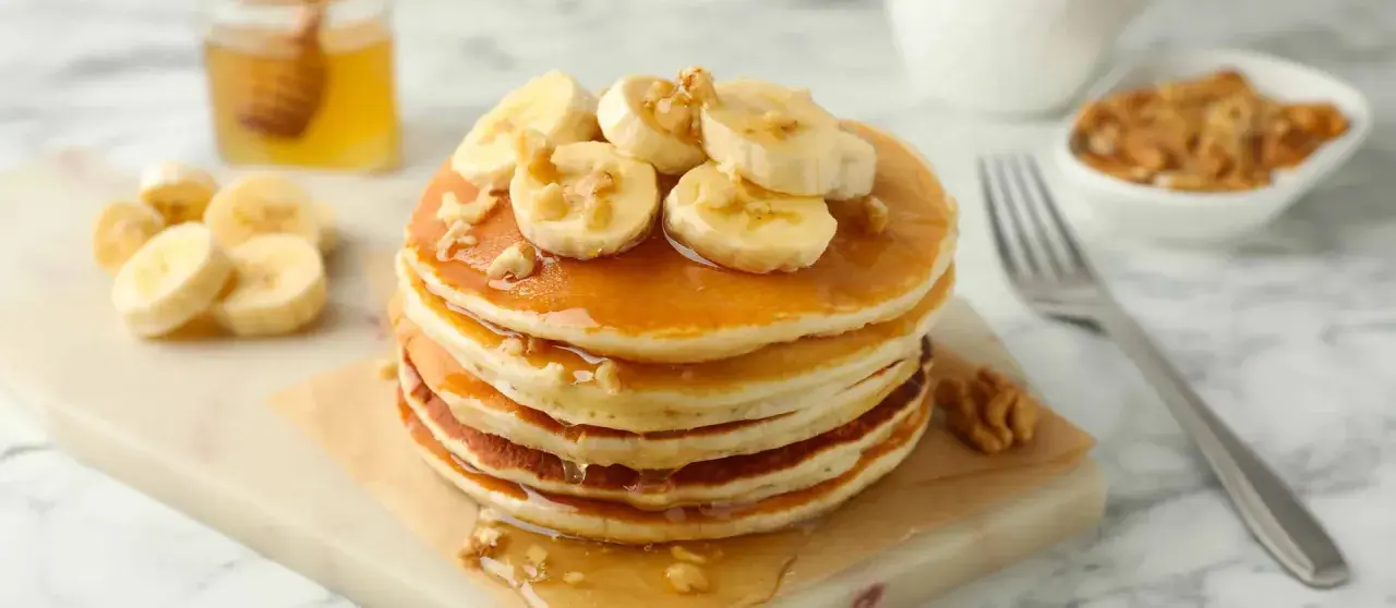 Pancake light con banane e noci, inzuppati nello sciroppo d'acero. Un piacere per gli occhi e per il palato.