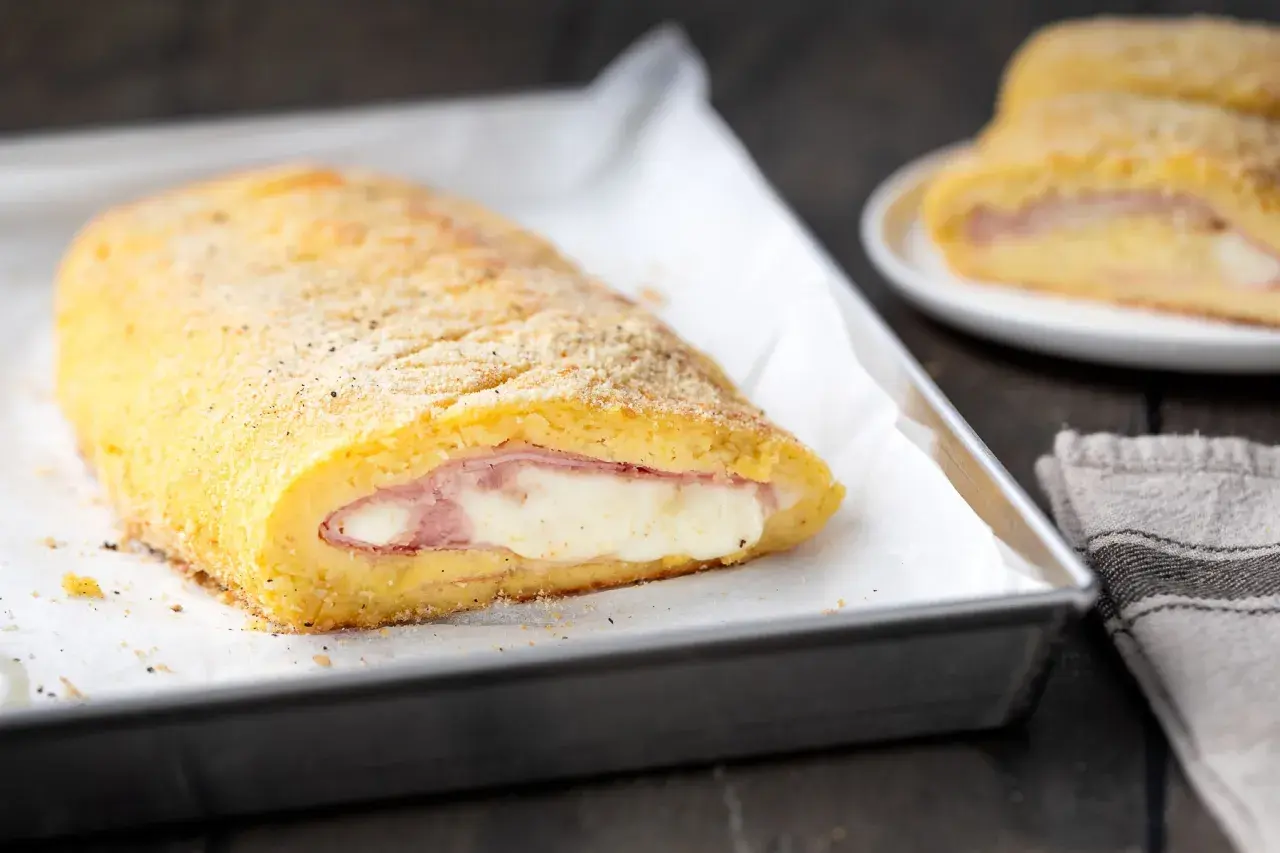 Polpettone di patate ripieno di prosciutto e formaggio filante, dorato e croccante, pronto per essere gustato.
