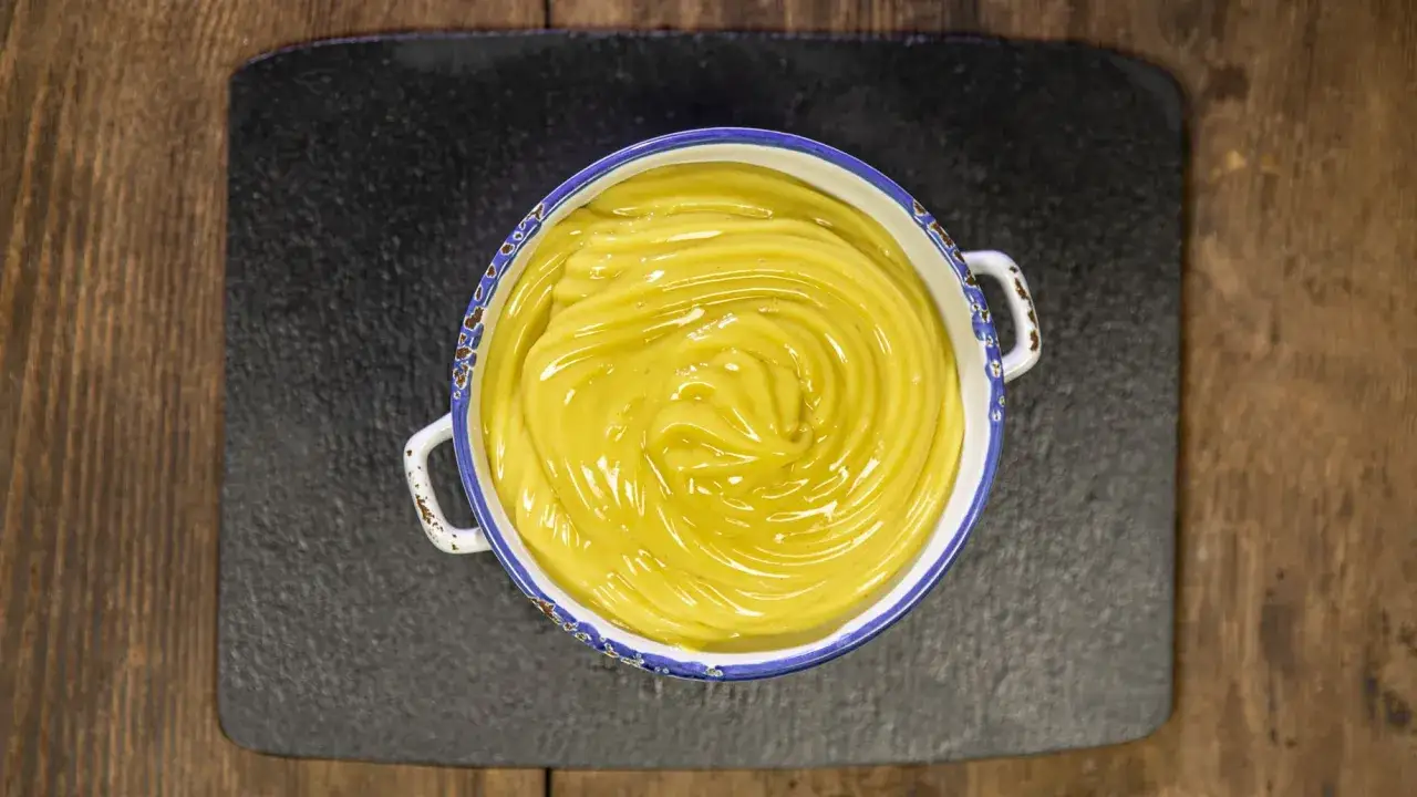 Crema pasticcera vegana, liscia e lucida, in una ciotola con bordo decorato, pronta per farcire dolci.