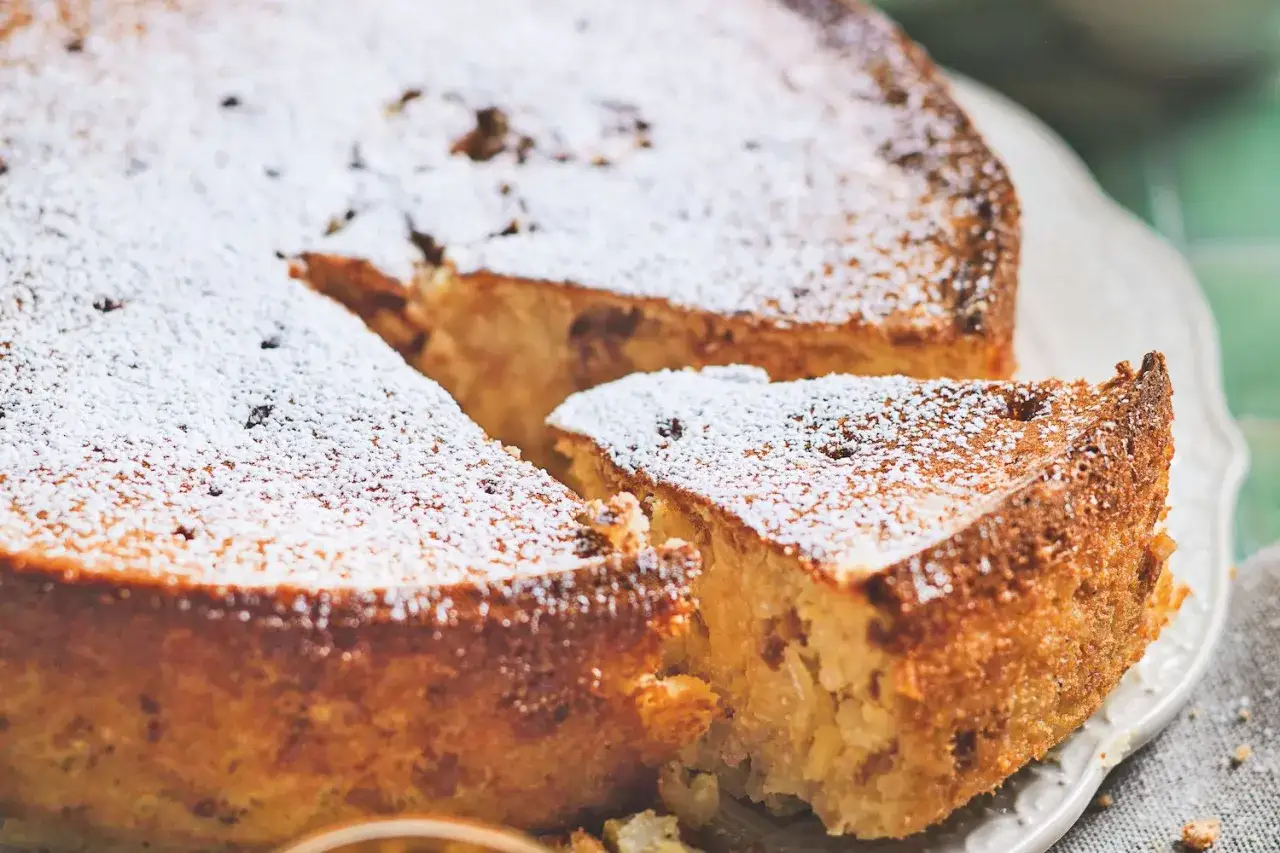 Una fetta di torta di riso, cosparsa di zucchero a velo, mostra la sua consistenza morbida e dorata.
