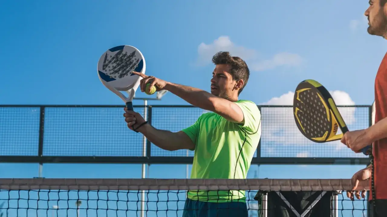 Uomo con racchetta da padel, mostra la palla e la sua impugnatura continental, pronto a servire.