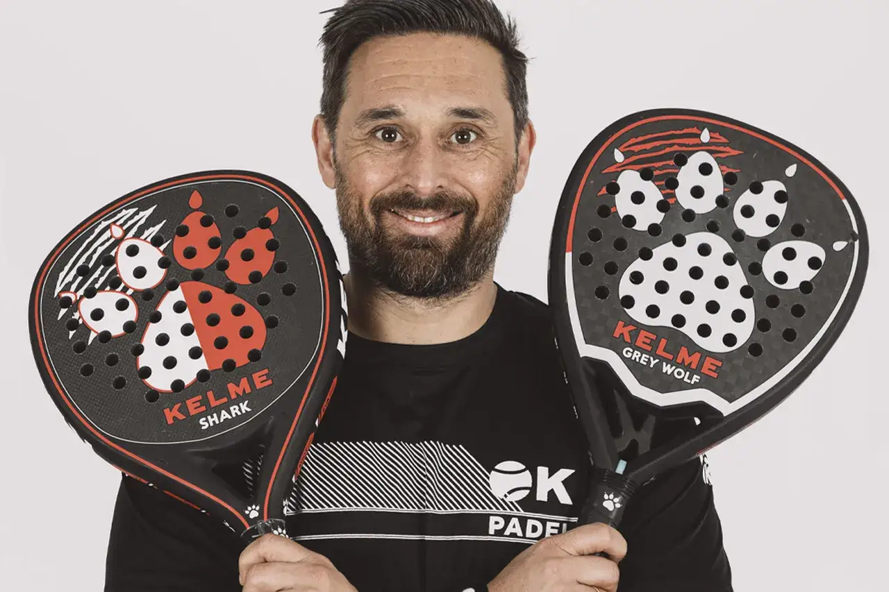 Mati Diaz sorride tenendo due racchette da padel Kelme con impronte di zampe.