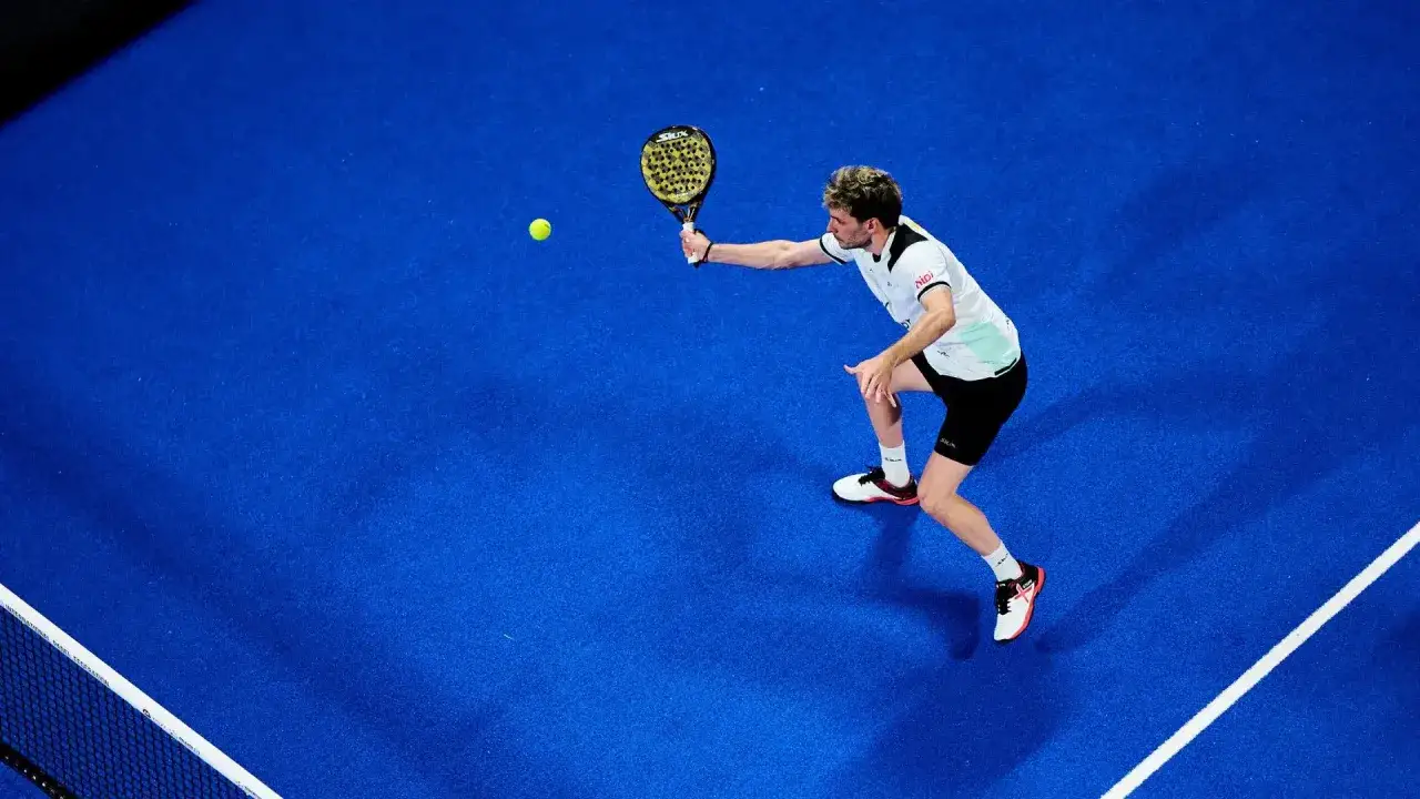 Giocatore di padel in azione, colpisce la palla con una racchetta, eseguendo un lob perfetto.
