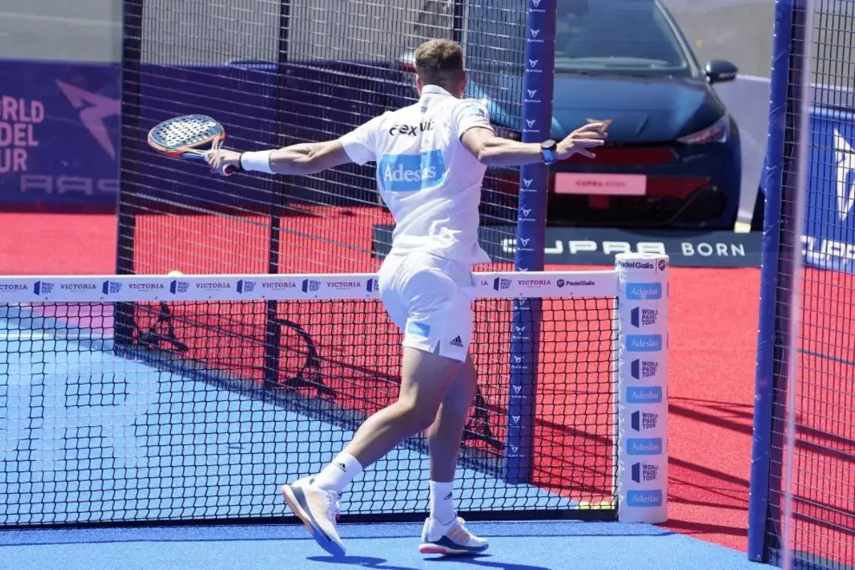 Giocatore di padel in azione, con la racchetta pronta per colpire. La sua maglia bianca con logo