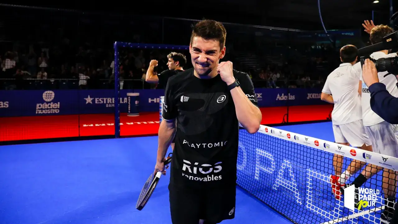 Martin padel esulta sul campo blu, con il pubblico sullo sfondo. La sua espressione è di pura gioia dopo una vittoria.