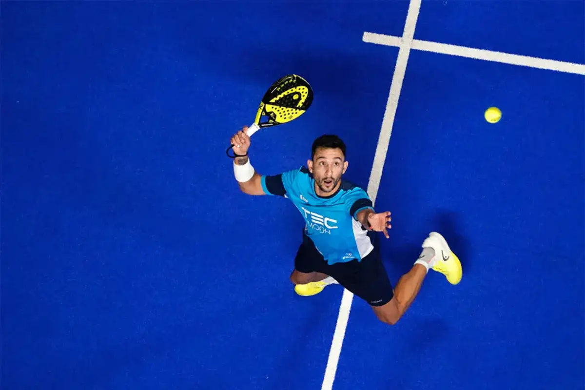 Alex Ruiz in azione sul campo da padel, pronto a colpire la palla con la sua racchetta gialla.