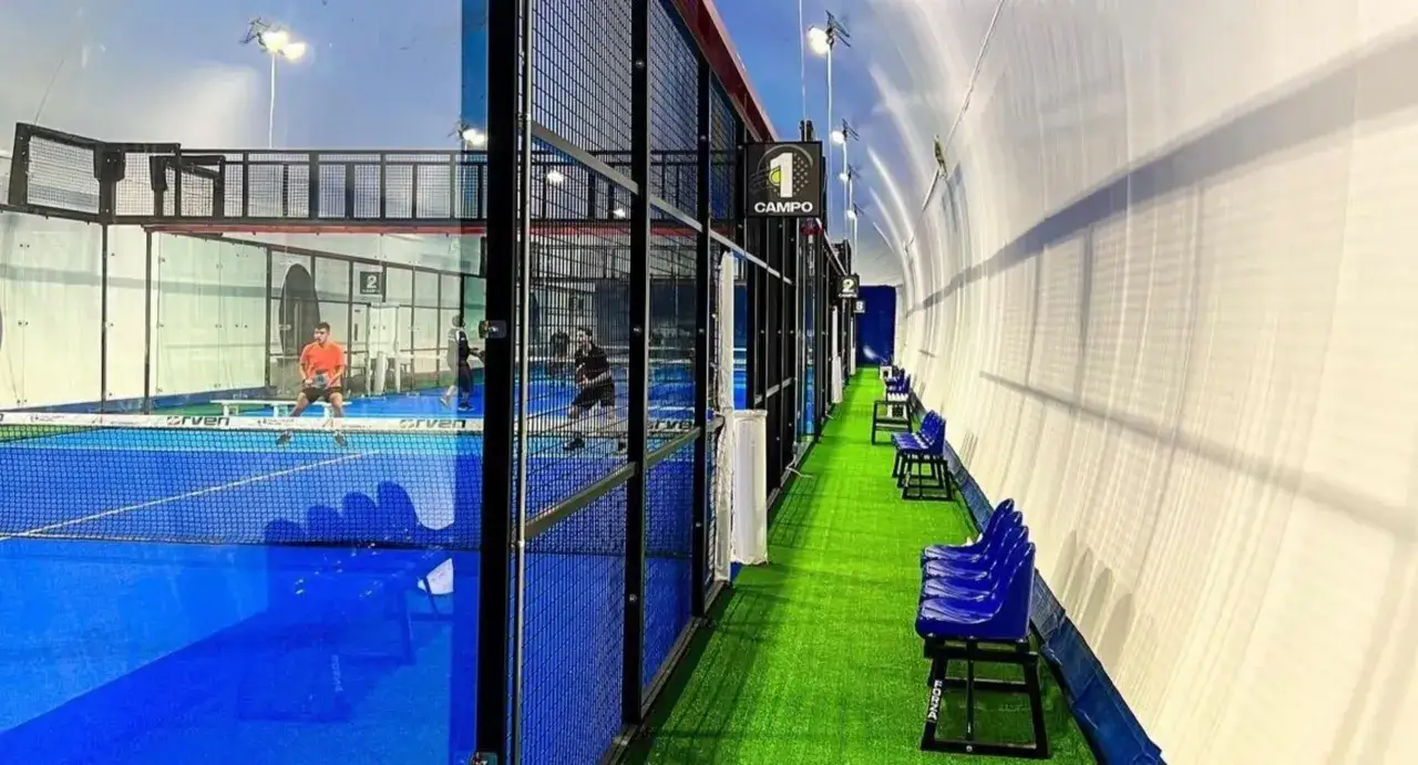 Campi da padel indoor con giocatori in azione. L'atmosfera è quella di un torneo di Europa Padel, con tribune pronte ad accogliere il pubblico.