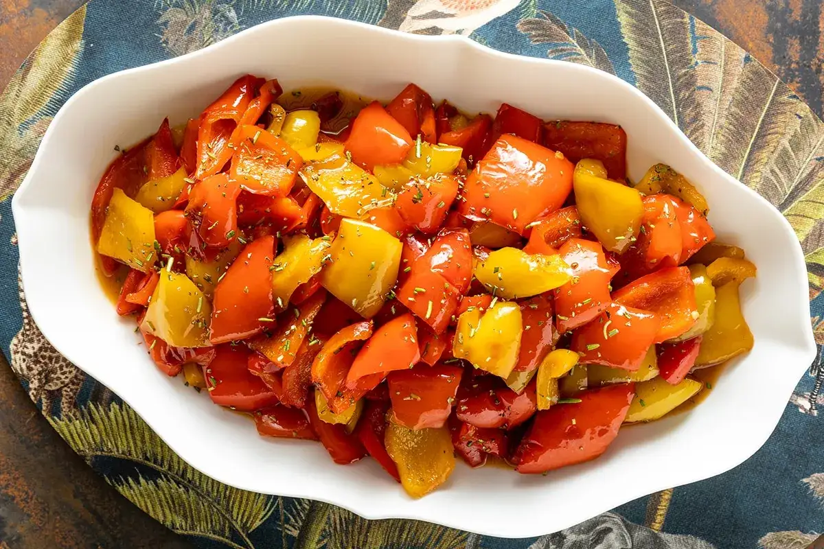 Peperoni in agrodolce, un contorno colorato e saporito, servito in una ciotola bianca su un tovagliolo decorato.