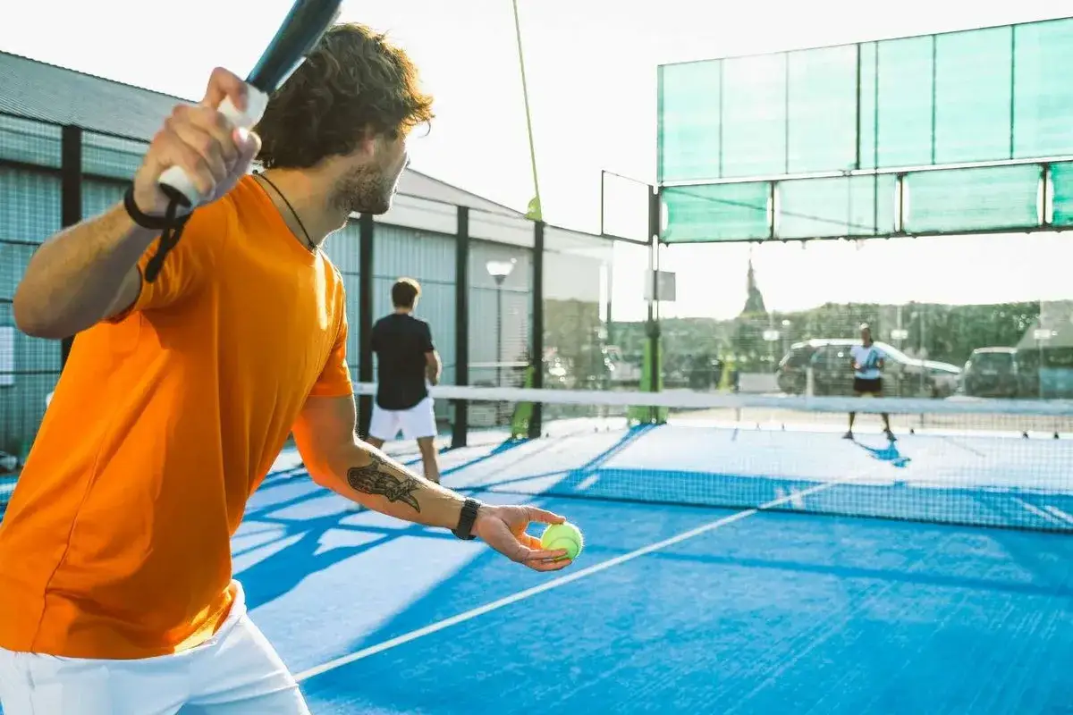 Uomo con racchetta e palla, pronto a giocare a padel. Ottimi trucchi padel principianti per iniziare.