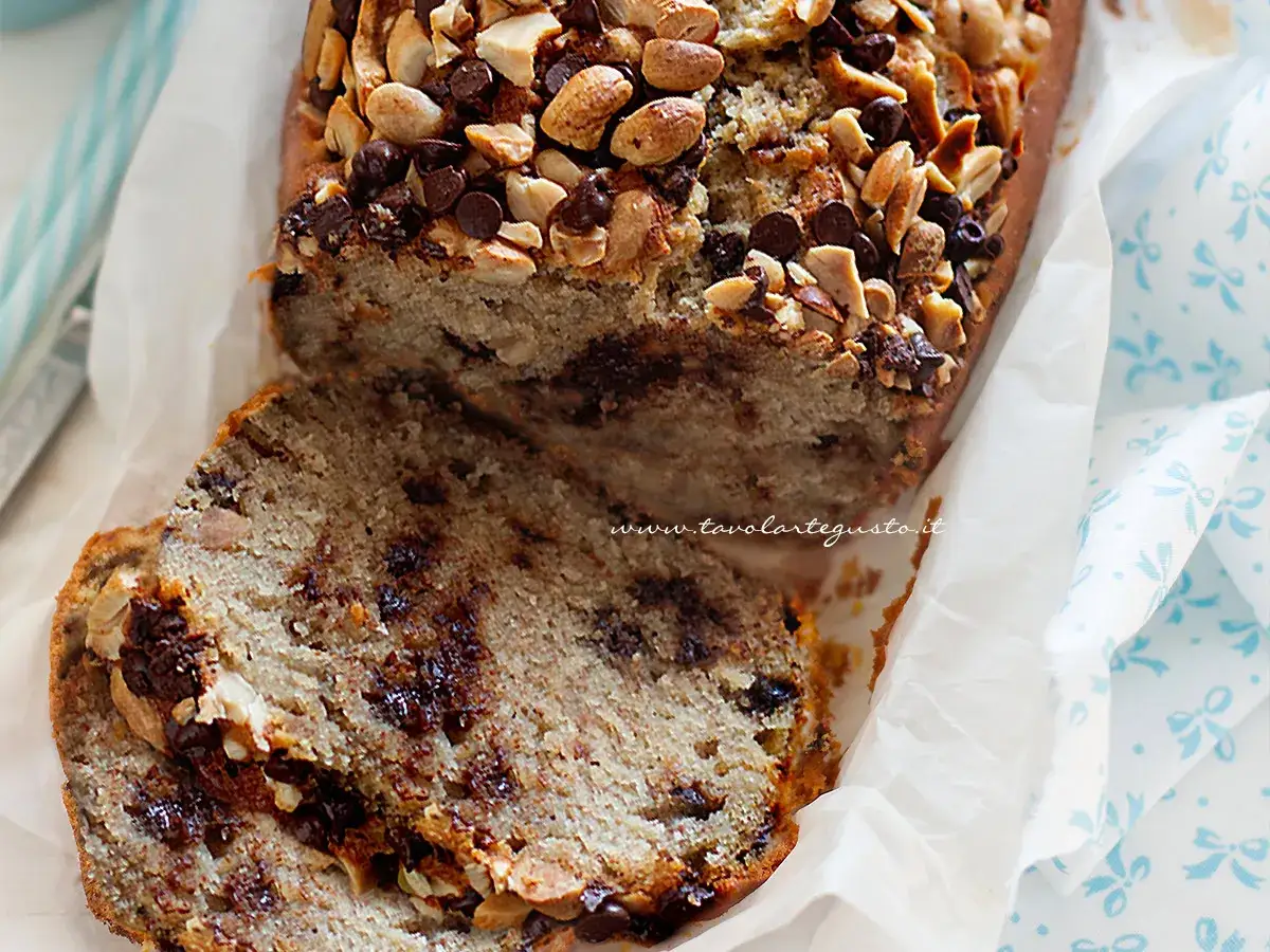Banana bread senza burro, soffice e goloso, con gocce di cioccolato e noci tostate in superficie.