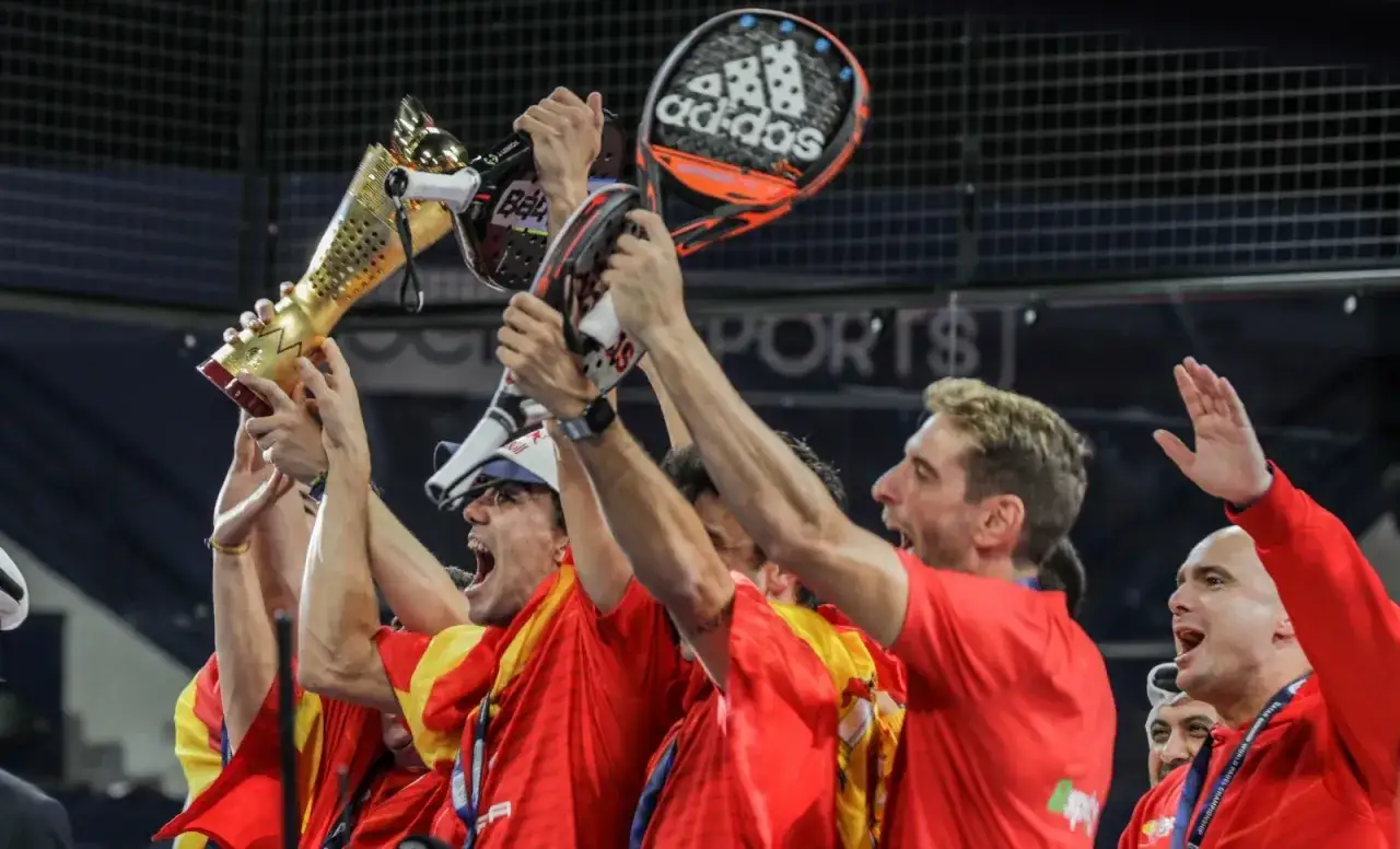 Un giocatore padel spagnolo festeggia la vittoria sollevando il trofeo e una racchetta.