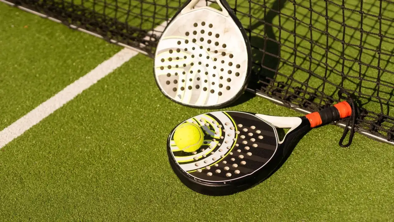 Due racchette da padel e una pallina sul campo in erba sintetica. Quanto dura una racchetta da padel? Dipende dall'uso!