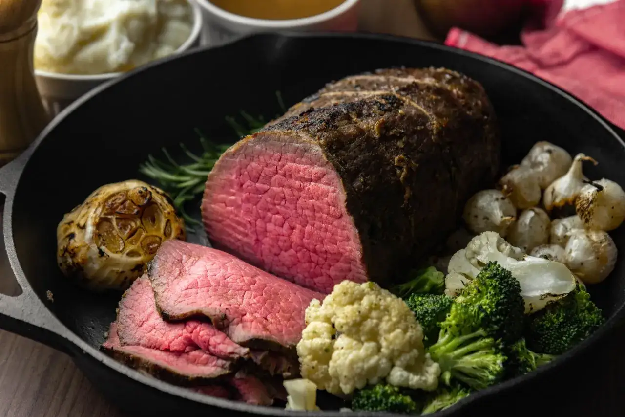 Roast beef succulento, affettato e servito in padella con contorni di broccoli, cavolfiore, aglio arrosto e rosmarino. La ricetta in pentola perfetta per un pranzo domenicale.