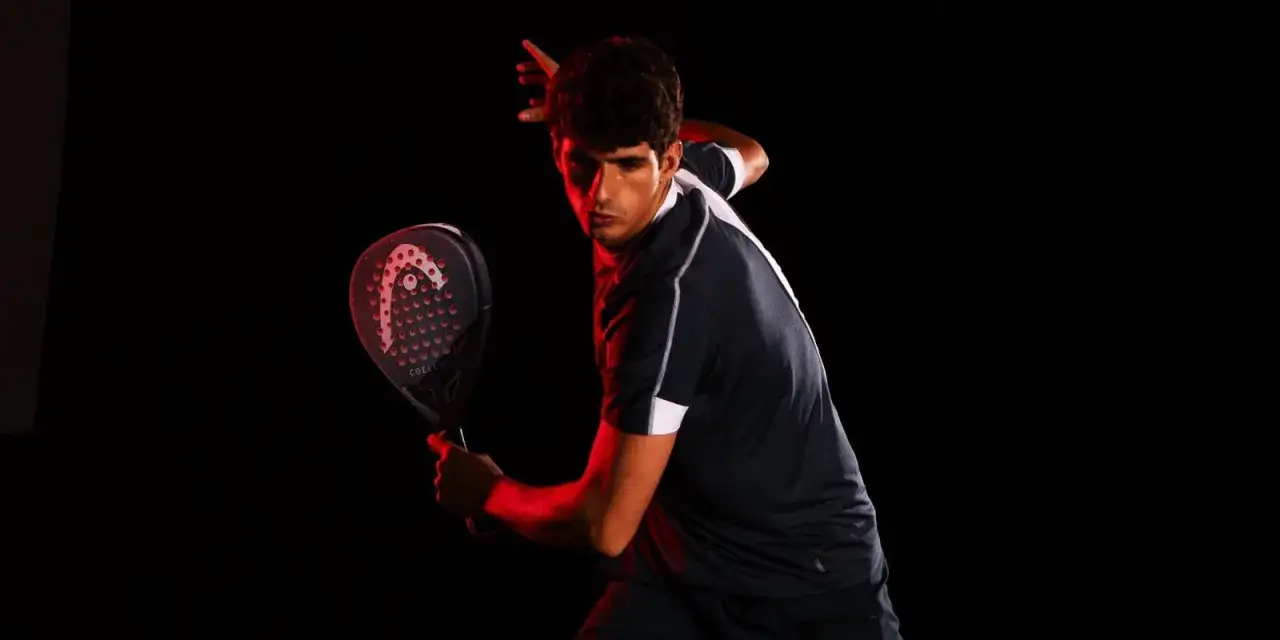 Giocatore di padel con racchetta Head, illuminato da luci rosse. Chissà quanto guadagna un giocatore di padel professionista.