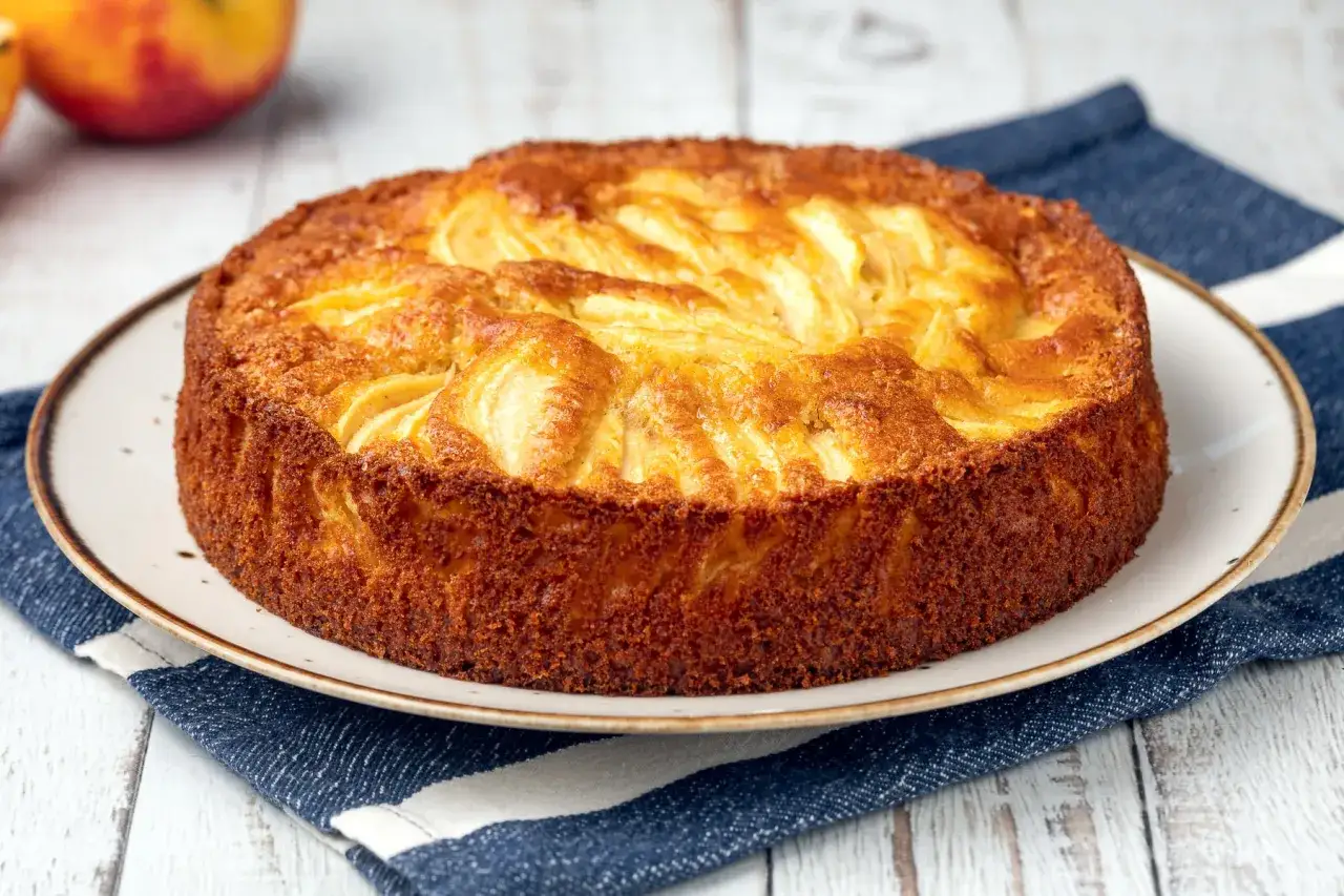 Torta di mele senza zucchero dorata e invitante, con mele a vista sulla superficie. Perfetta per una colazione sana.