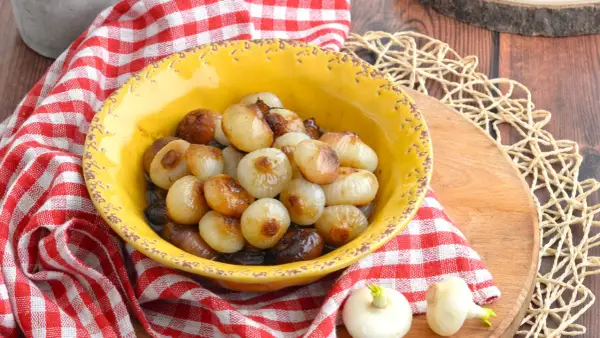 Cipolline caramellate in agrodolce, servite in una ciotola gialla con tovagliolo a quadri rossi.